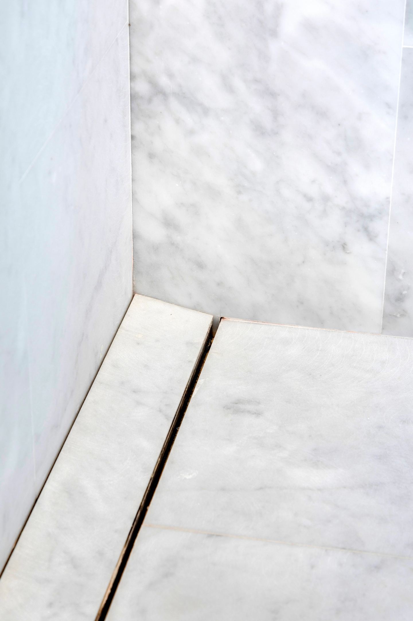 Linear drain cut flush into the marble shower floor