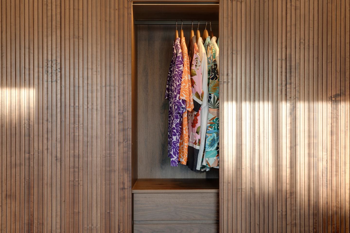 Clothes behind the sliding walnut slat doors