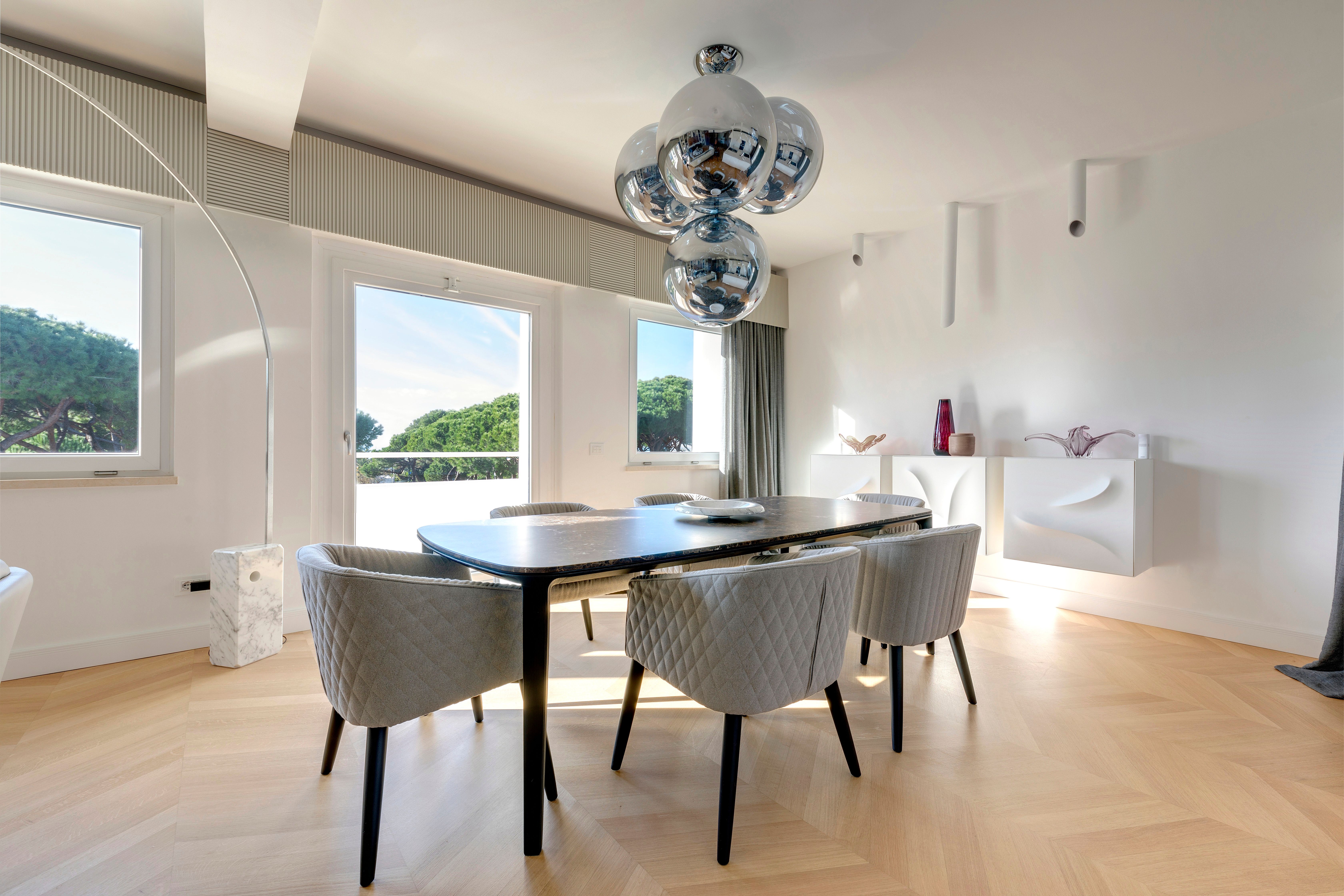Dining table and upholstered chairs below the cluster of mirrored globes