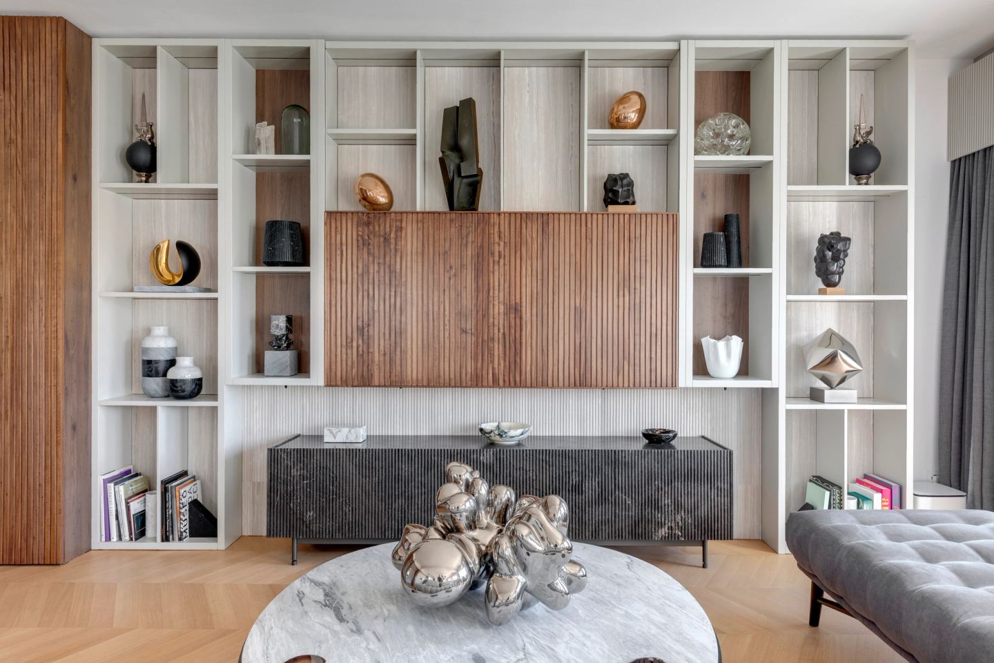 Shelving wall with ceramics and a walnut panel above the stone sideboard