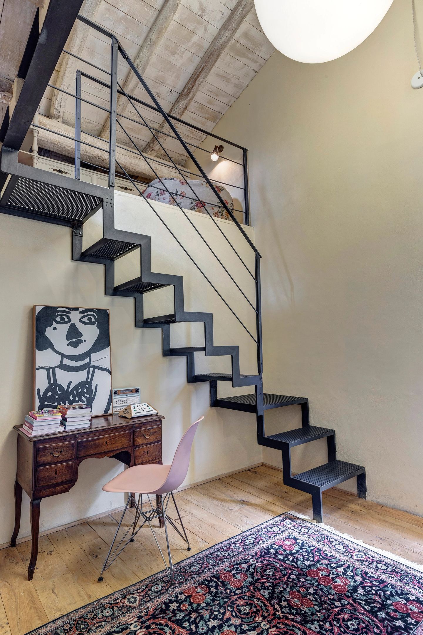 The stair climbing to the mezzanine, a painted portrait on the desk