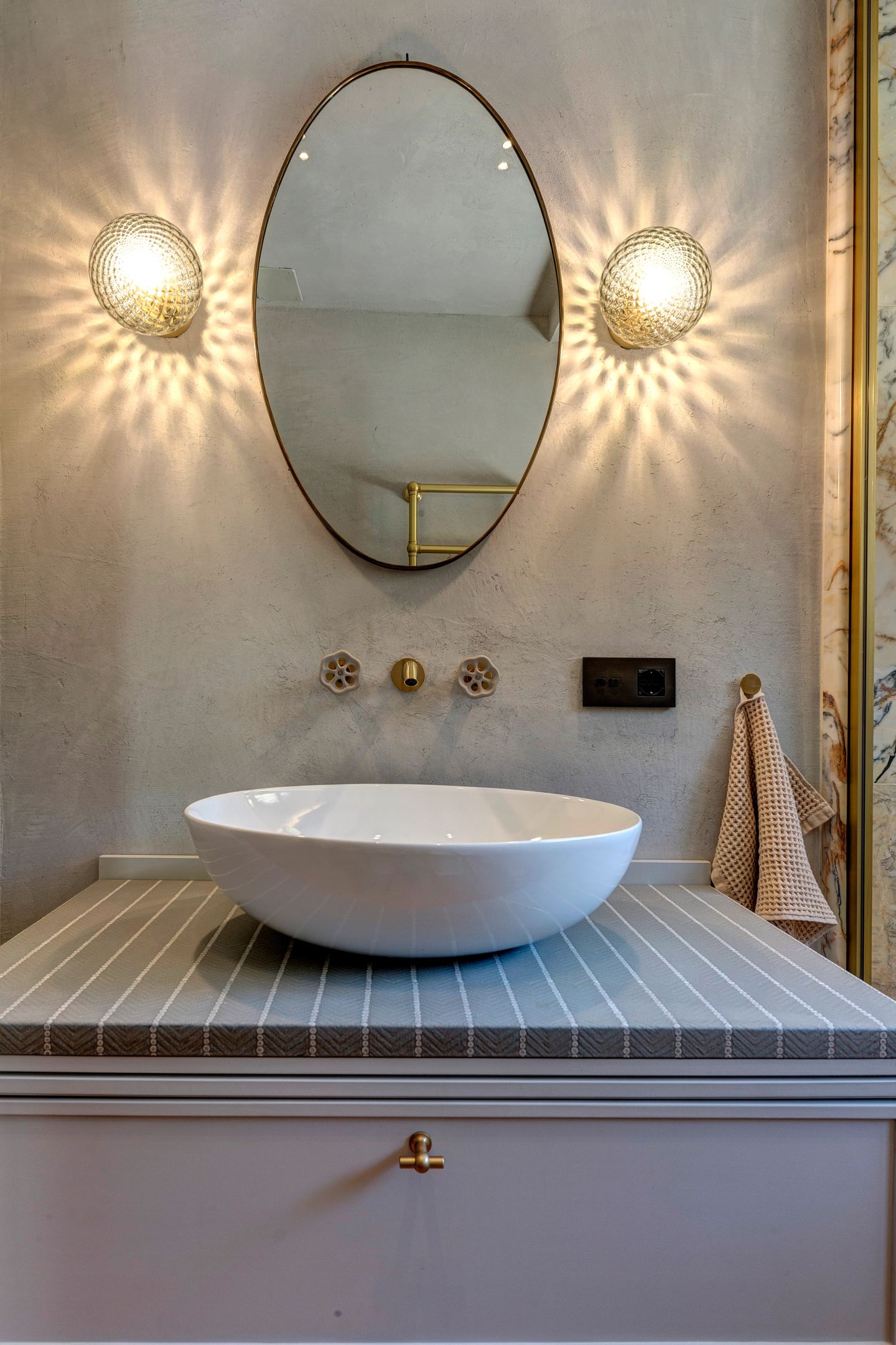 The oval mirror between two wall lights