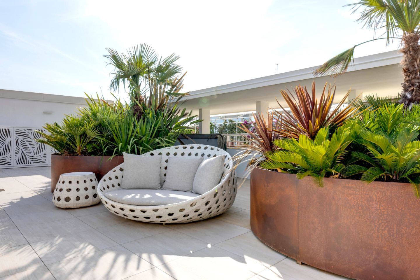 Daybed tondo in intreccio e pouf tra le fioriere