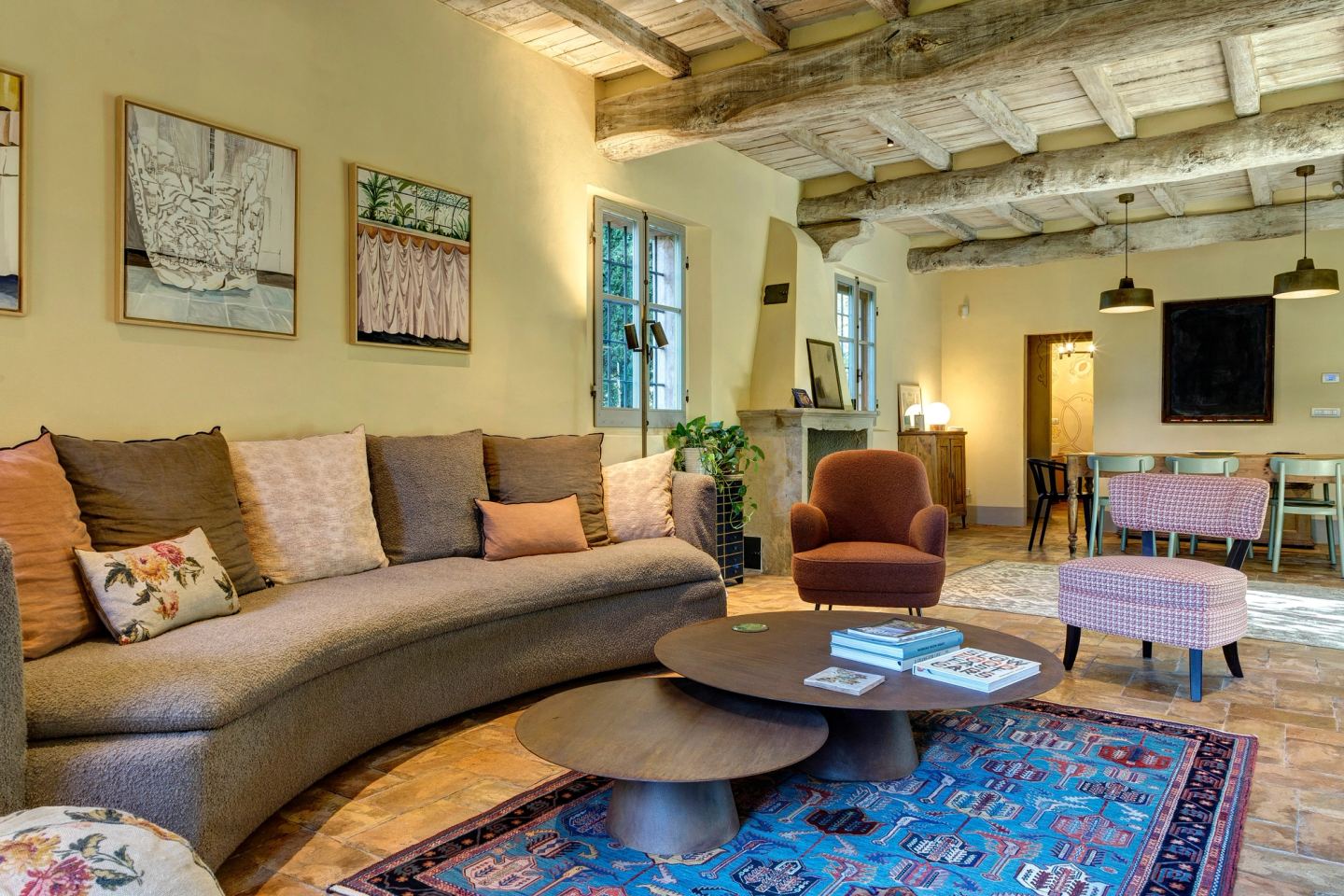 The ground-floor living room: the long curved sofa, round tables, the dining room beyond