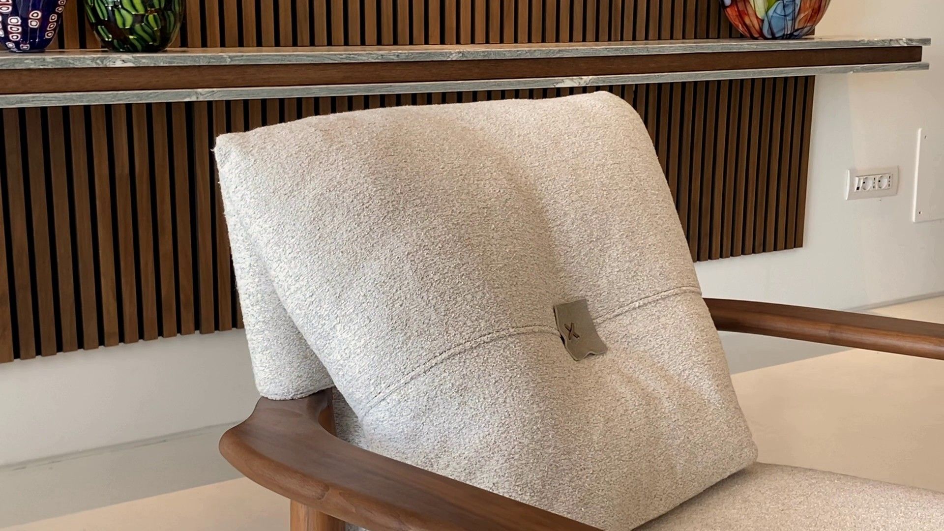 A Lisa armchair: the walnut arm and the pale back cushion with its leather tab