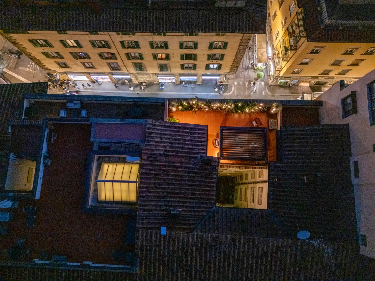 The lit terrace set into the dark roofs