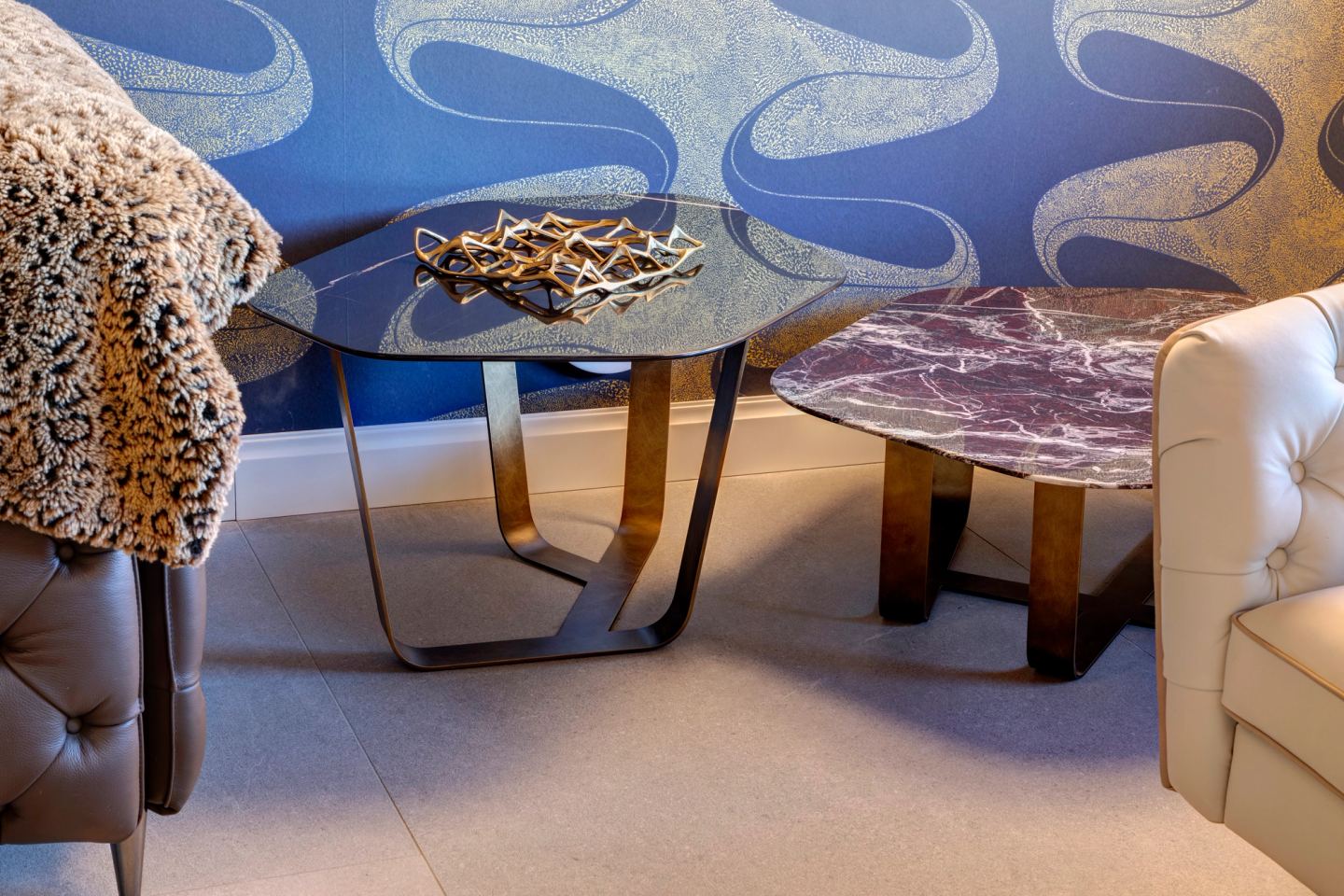 Glass tables between the armchairs, the patterned wall behind