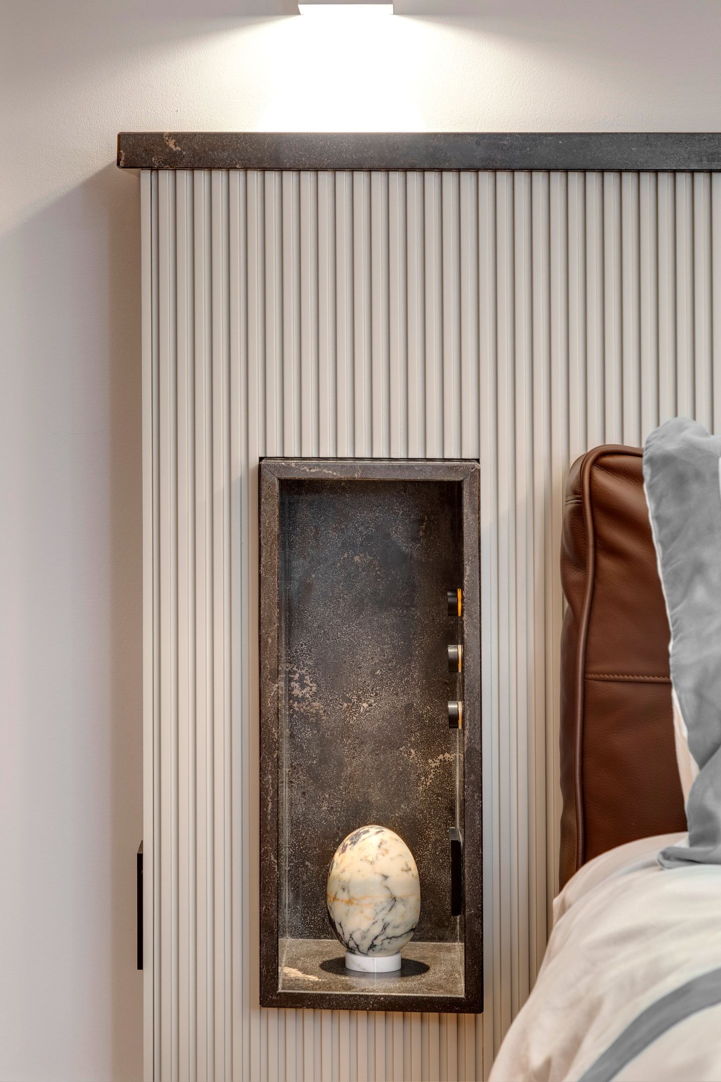 Lit niche beside the bed with a marble egg