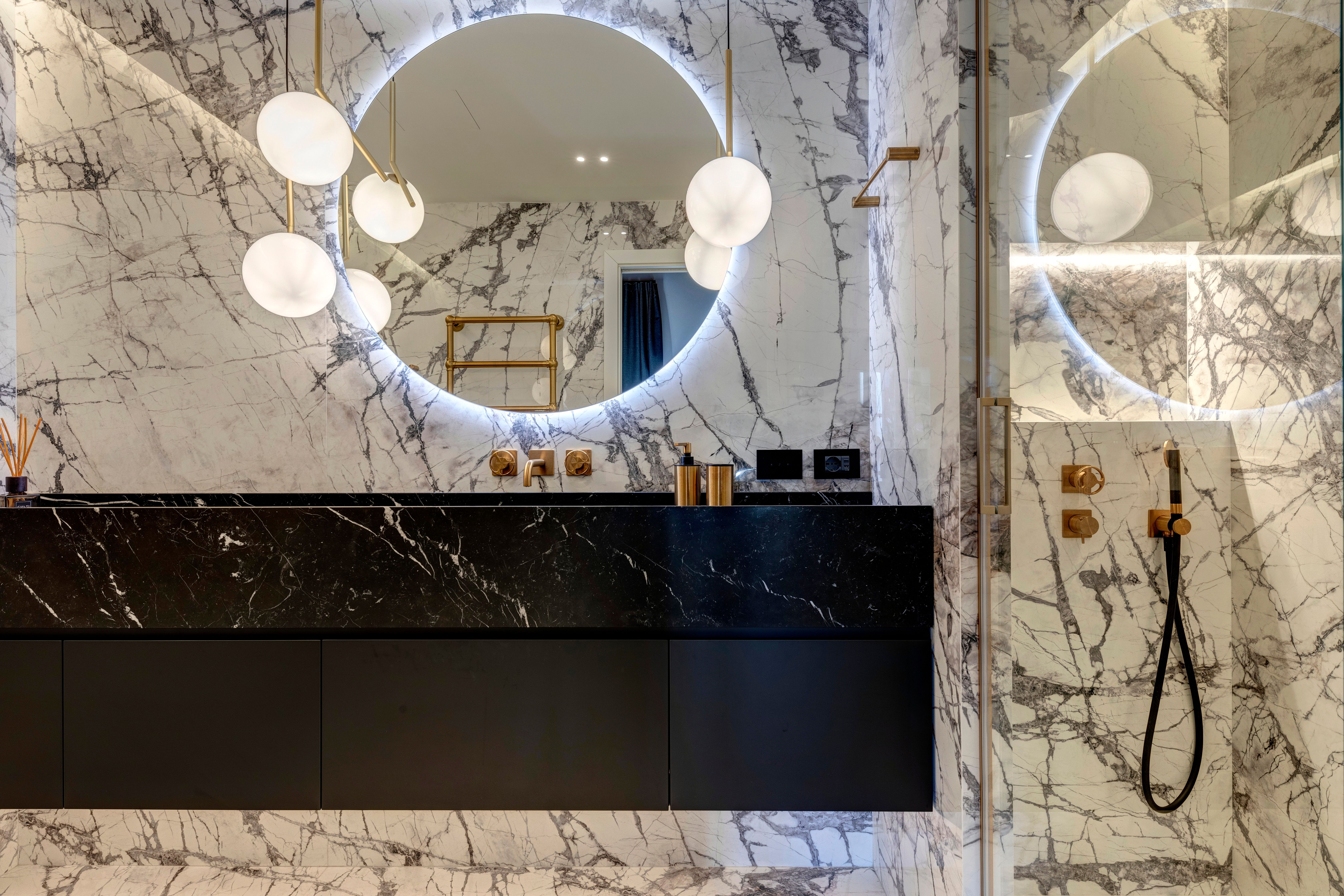 Black stone vanity below the round backlit mirror