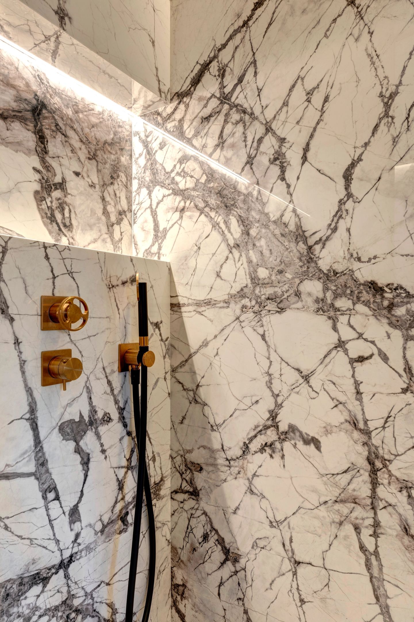 Brass shower controls on the veined marble