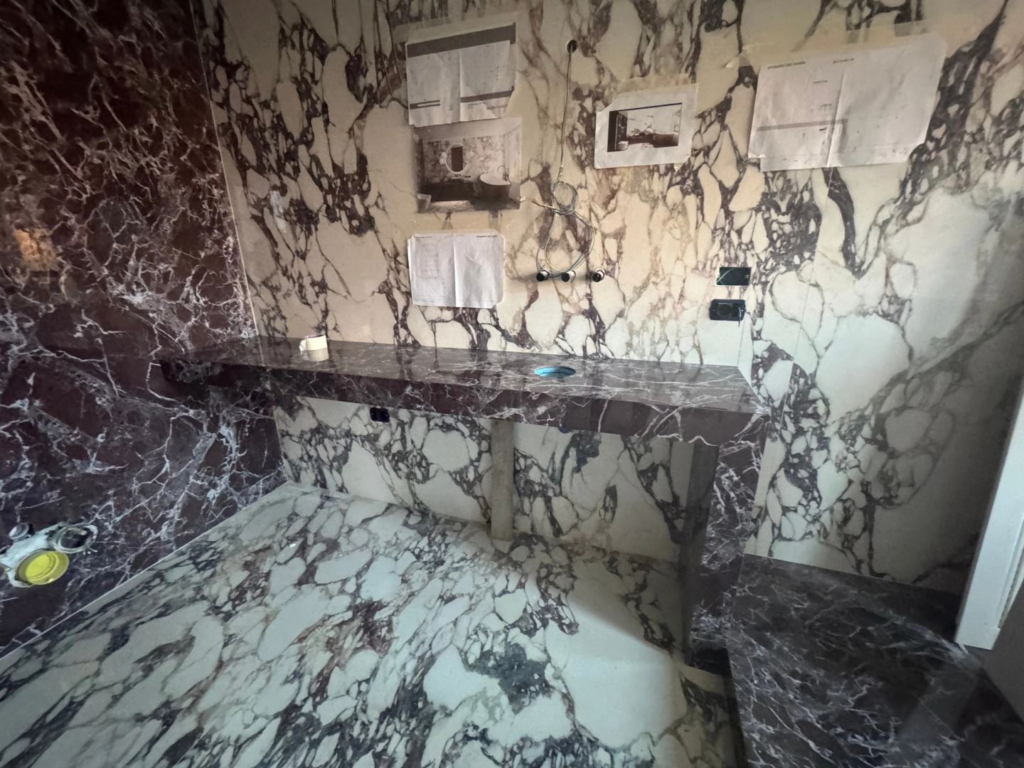 The vanity shelf in dark marble, notes taped to the wall