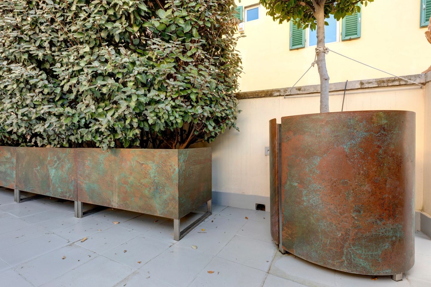 Una fioriera tonda e una lunga che si incontrano in un angolo della terrazza