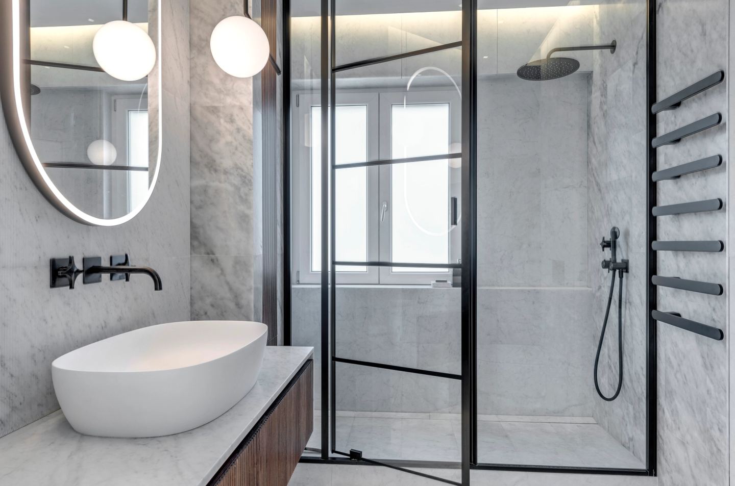 Basin on the marble top, shower behind the black-framed glass
