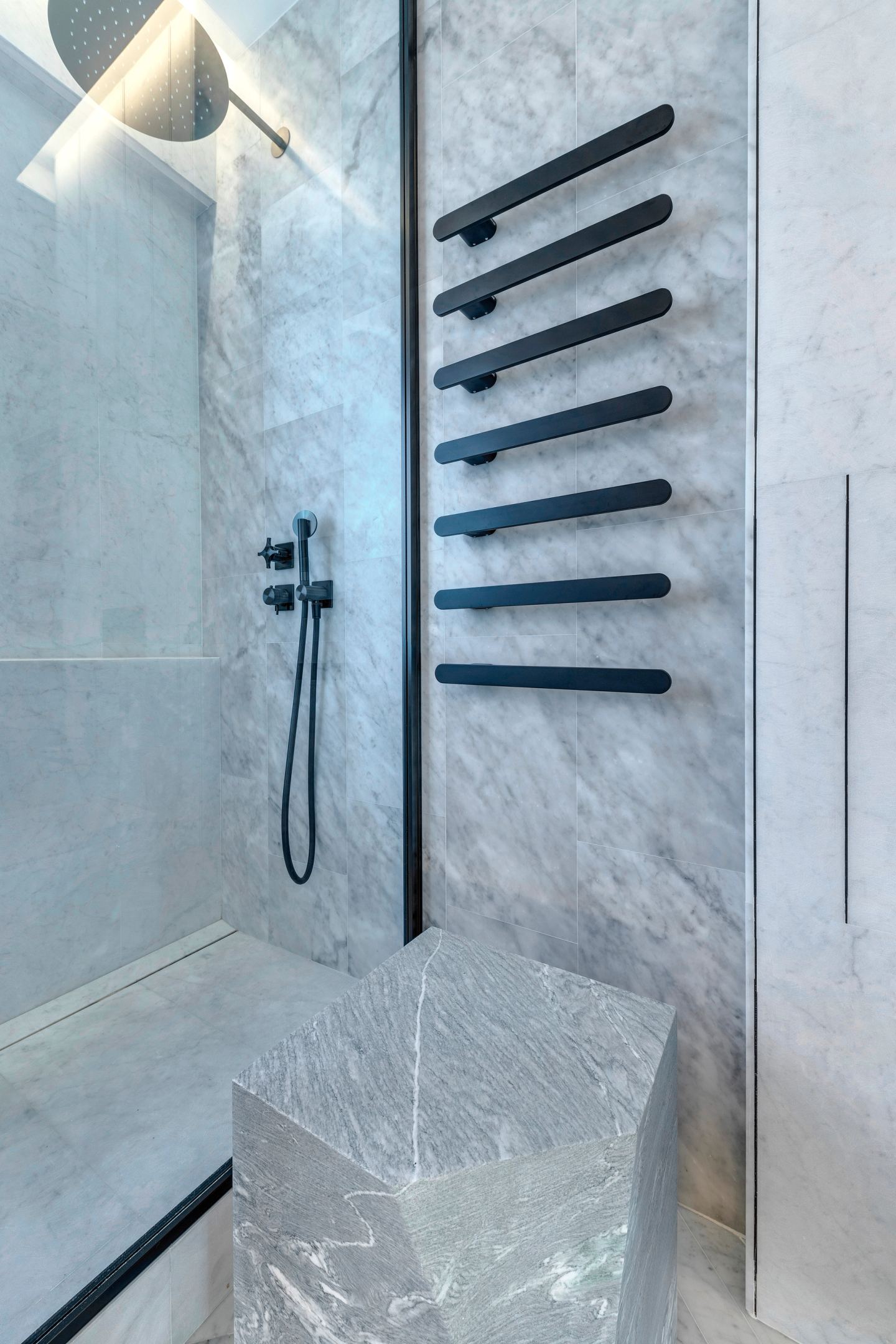 Walk-in shower with the black heated rail on marble