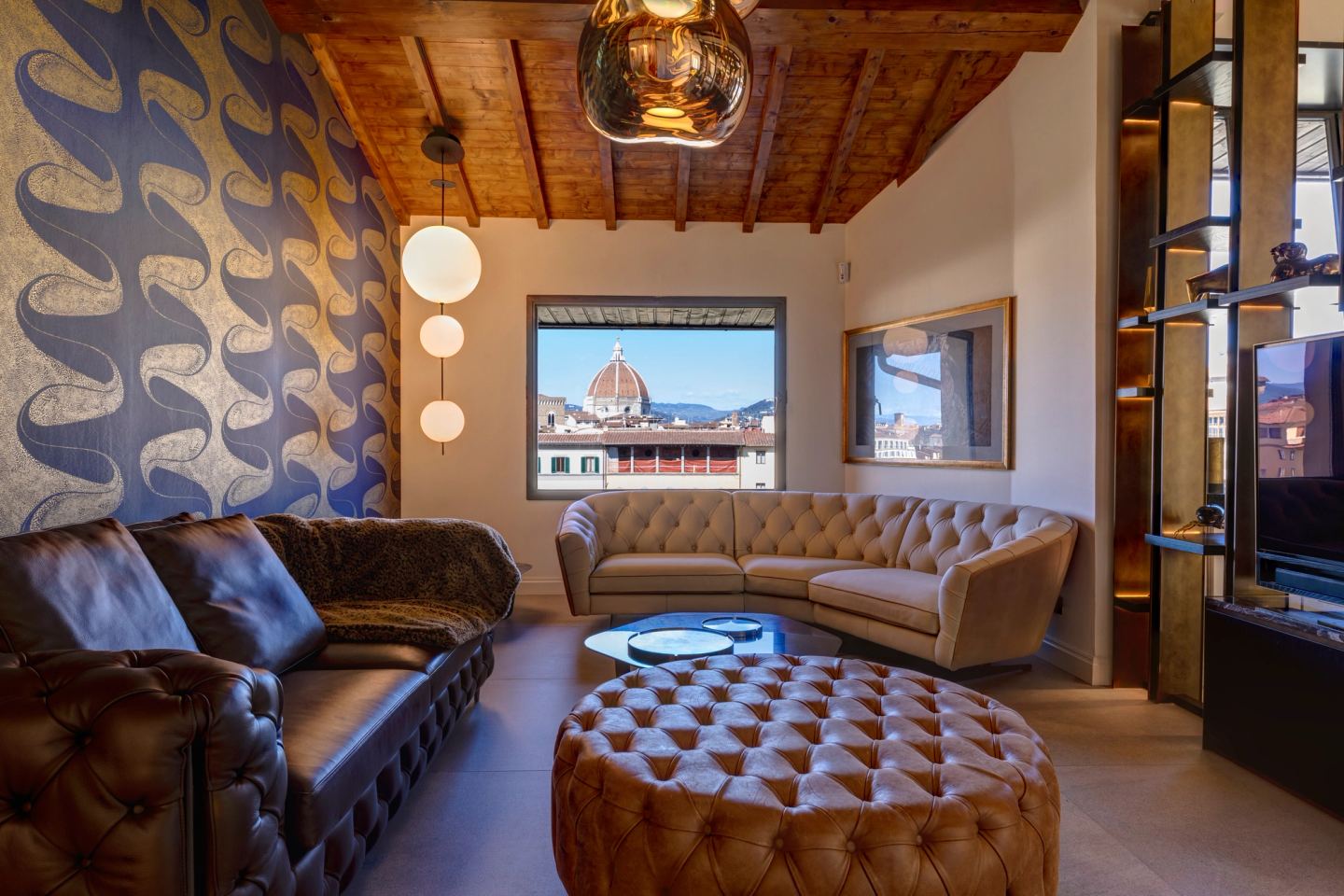 The living room under the beamed roof, the Duomo framed in the window