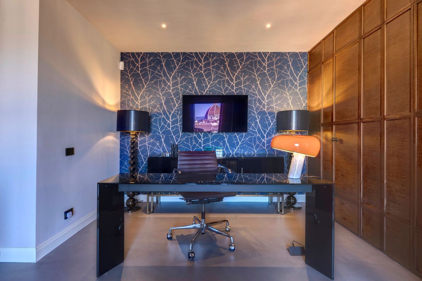 The study: black glass desk against the branch-patterned wall