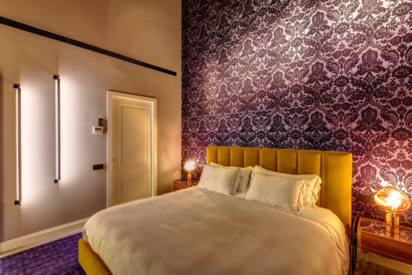 The bed at night between the vertical wall lights