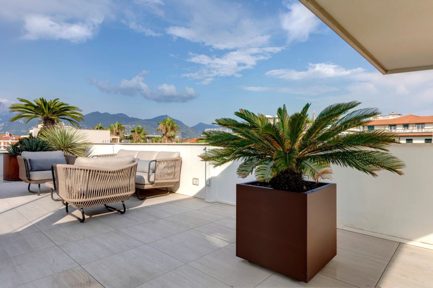 Rattan armchairs beside a square corten planter