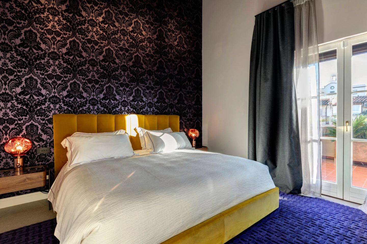 The bedroom with the terrace door open, curtains drawn back