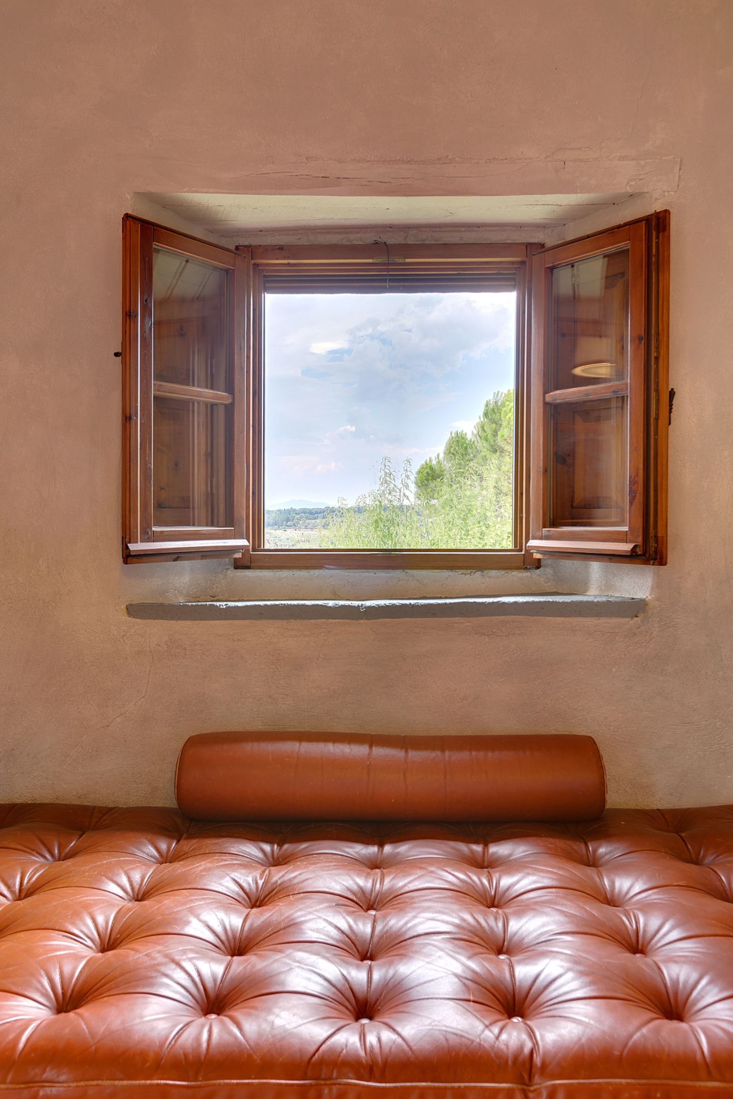 A buttoned leather bench below the shutters