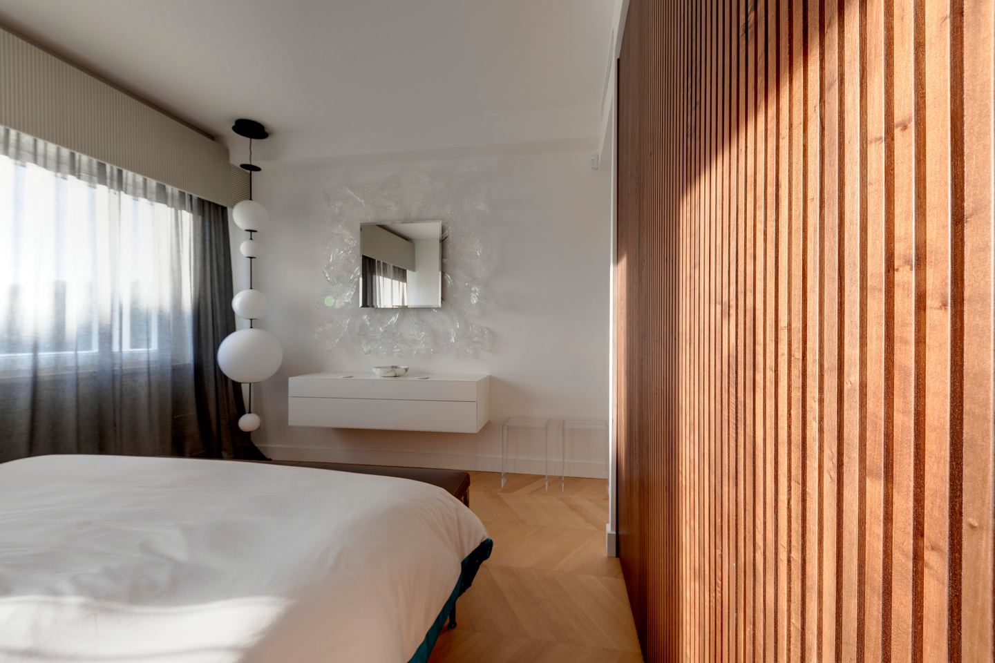Bed, sheer curtains and the floating console opposite