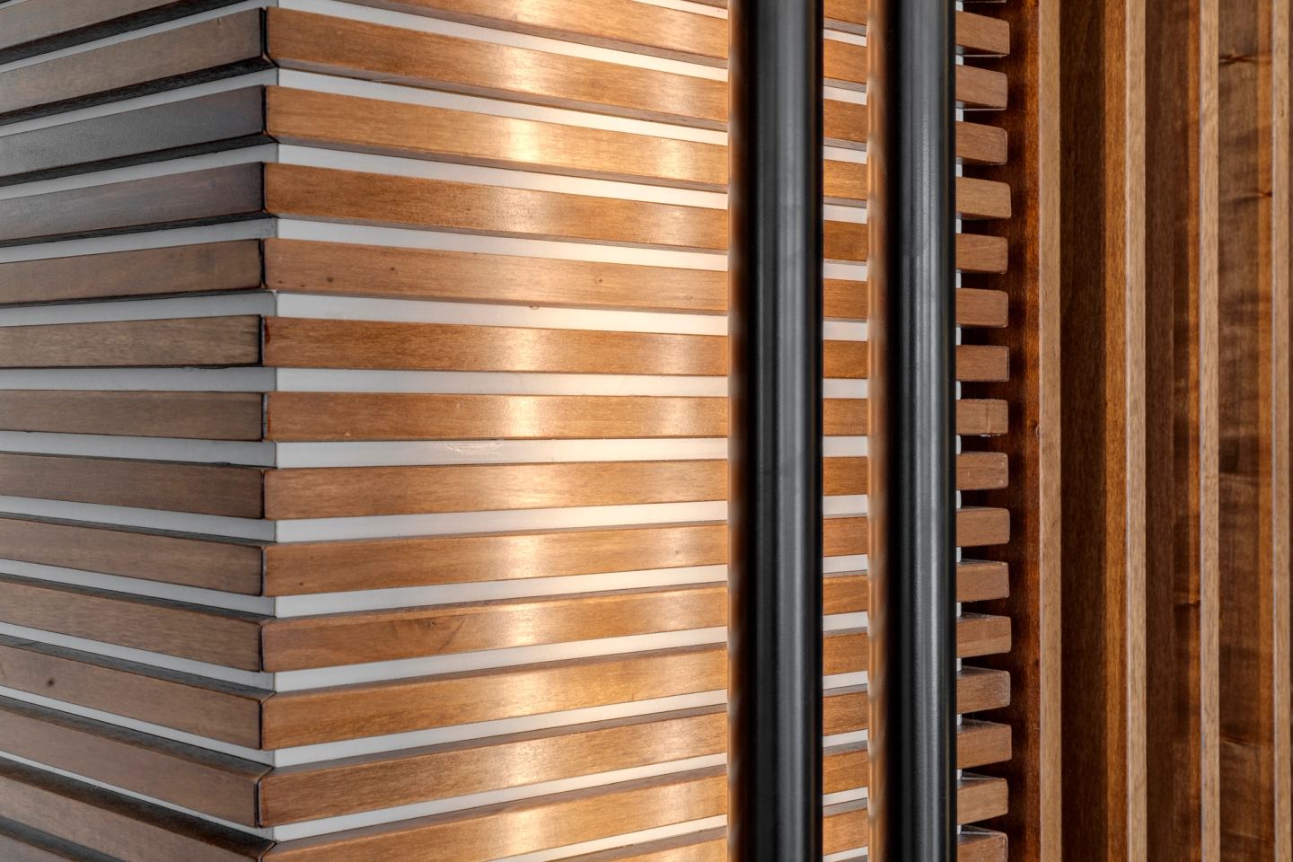 Walnut slats meeting at an external corner, three rhythms side by side