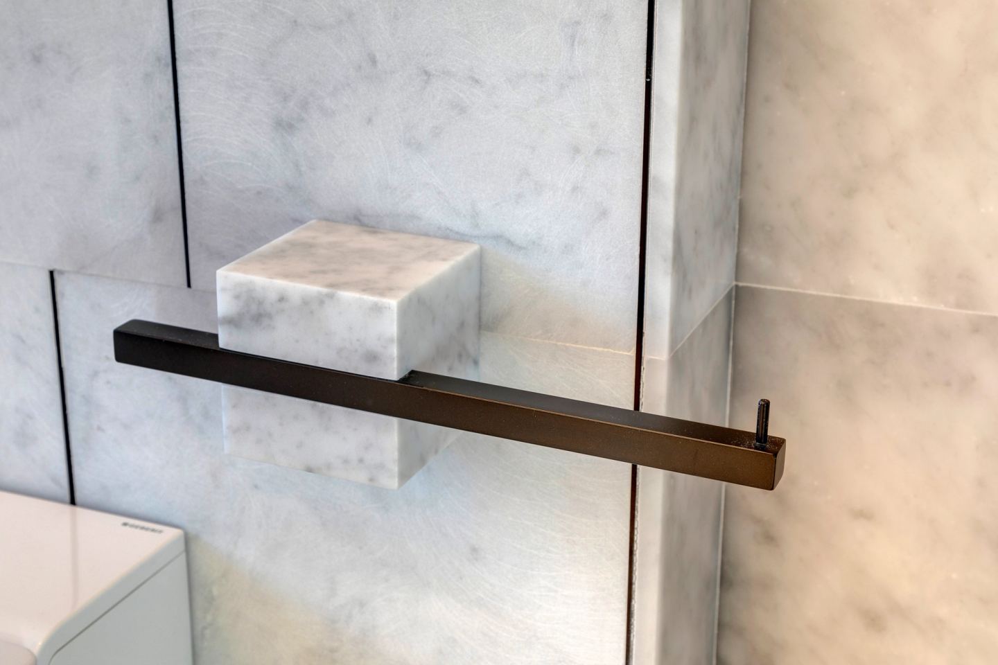 Marble shelf on a black steel bracket above the bath