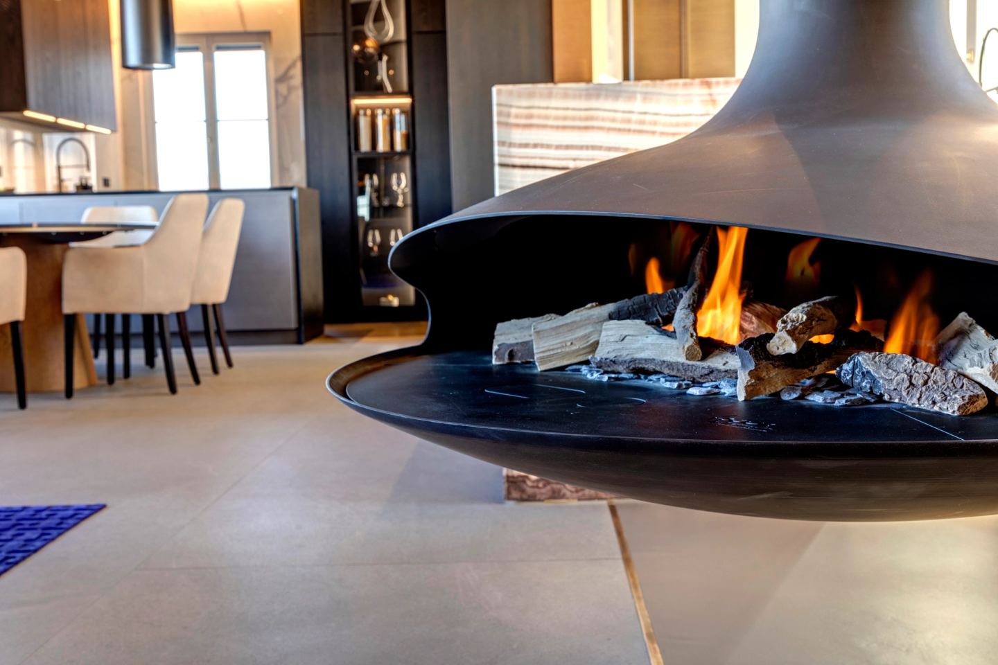 The suspended fireplace alight, its conical hood over the open hearth