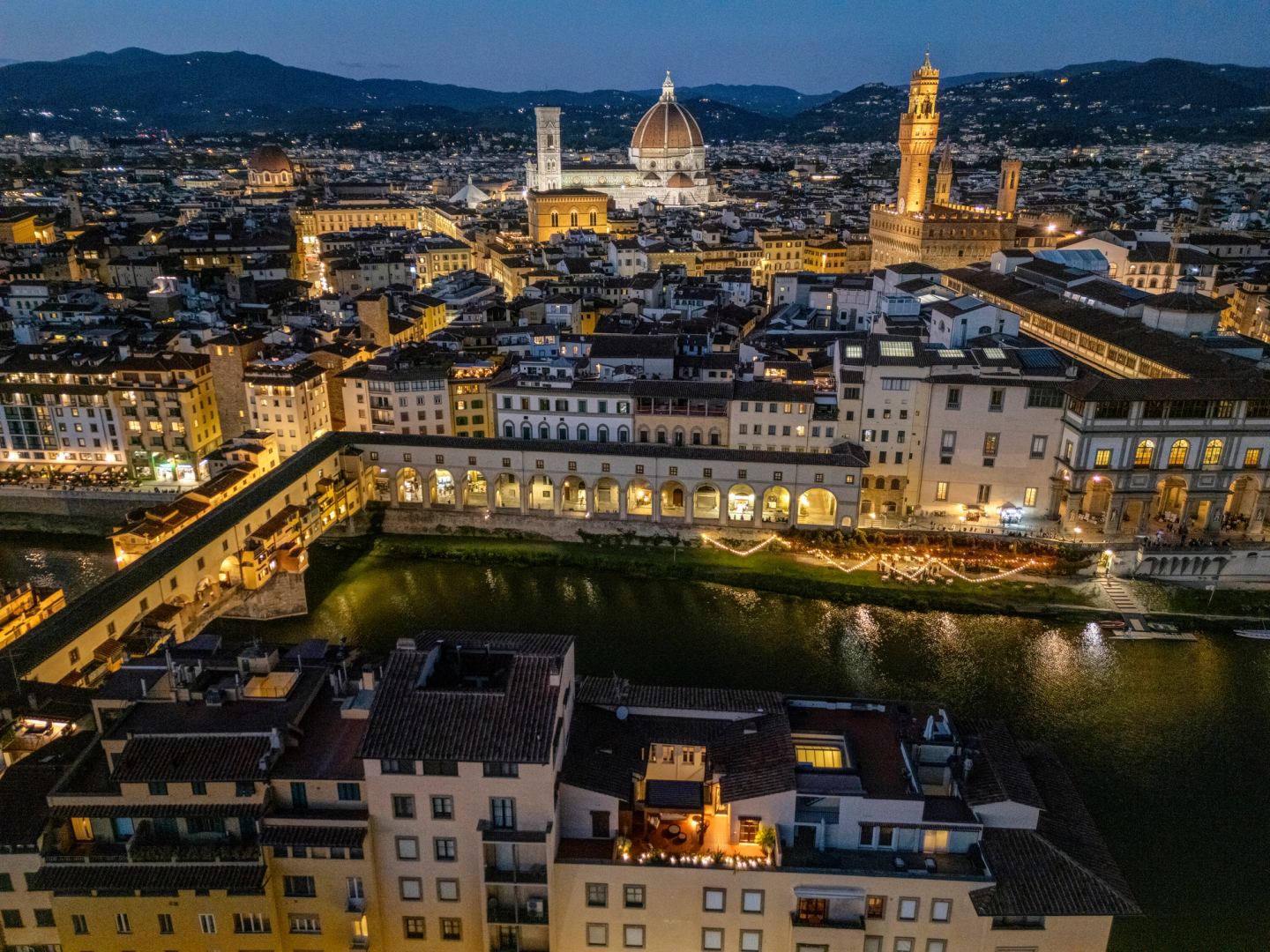 The city lit at dusk, Duomo and Palazzo Vecchio above the river