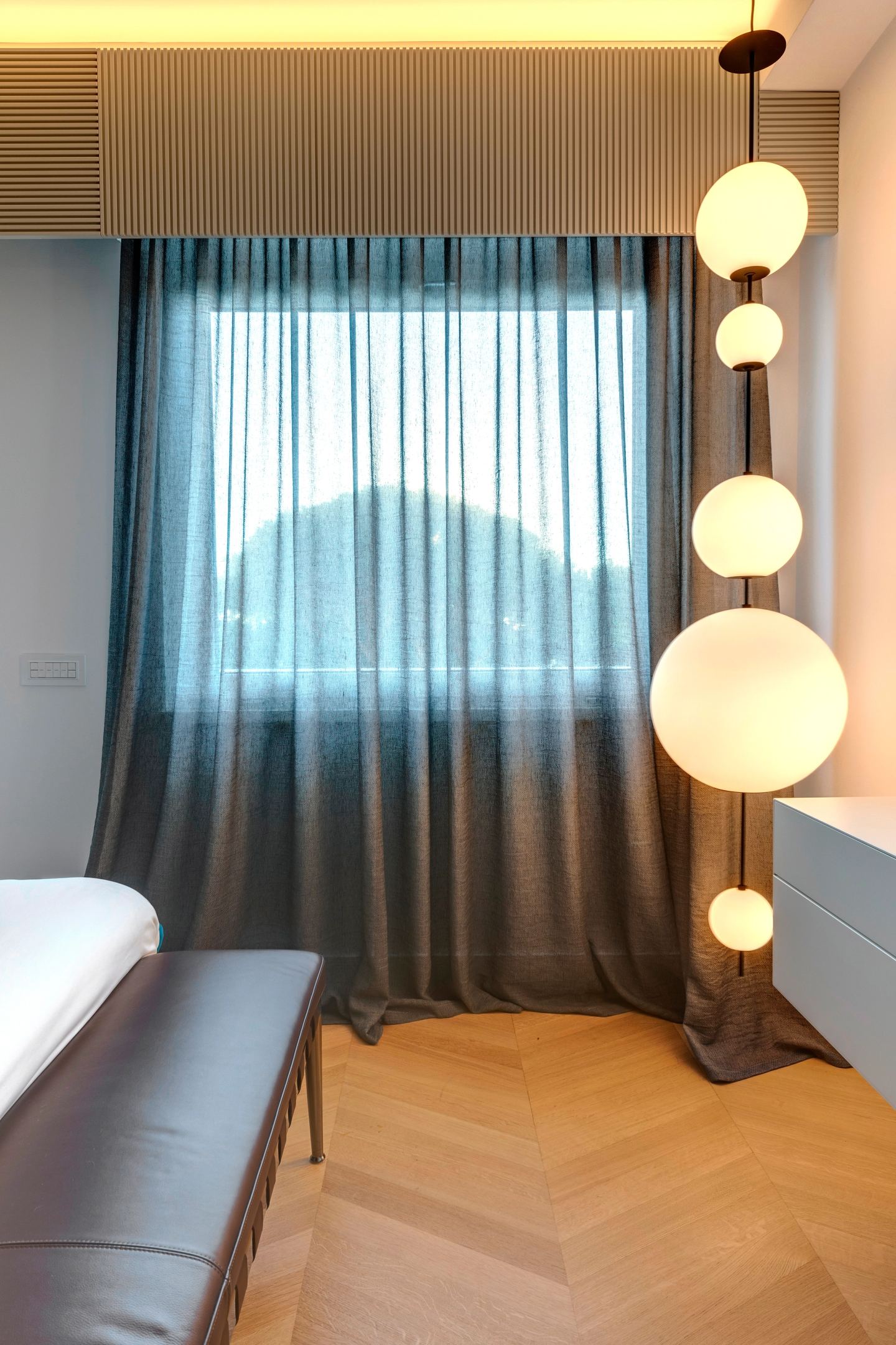 Curtains and globe pendants at the foot of the bed