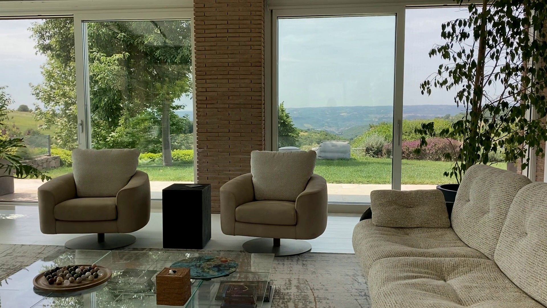 Two Hellis swivel armchairs against the glass doors and the garden