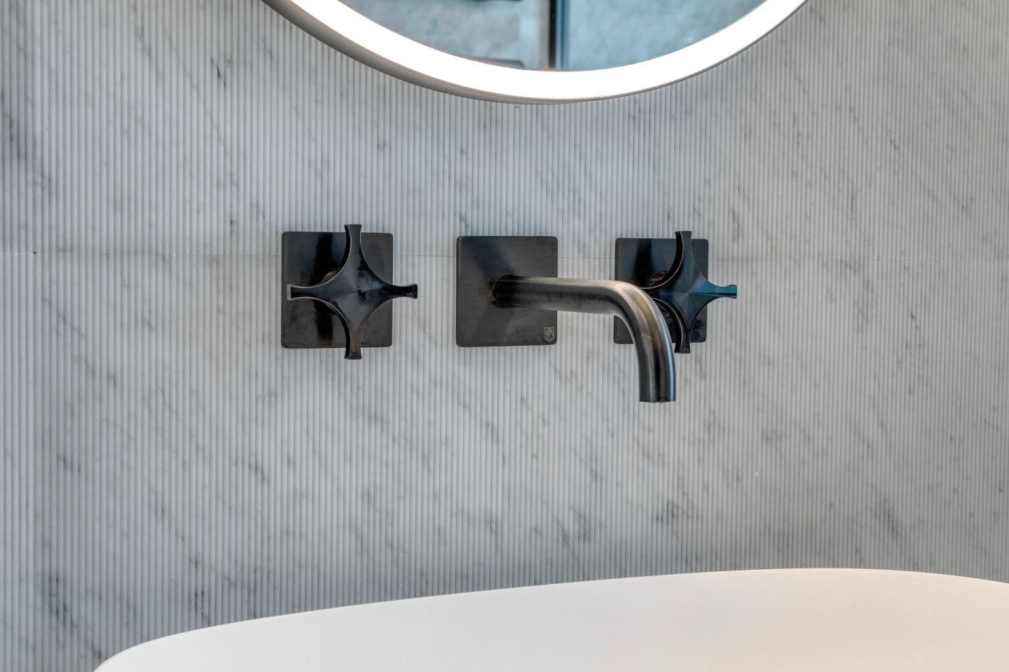 Black cross-handle mixer above the bath