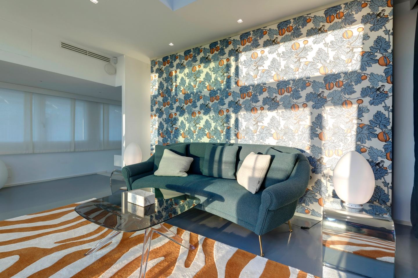 Sofa and low glass table below the papered wall