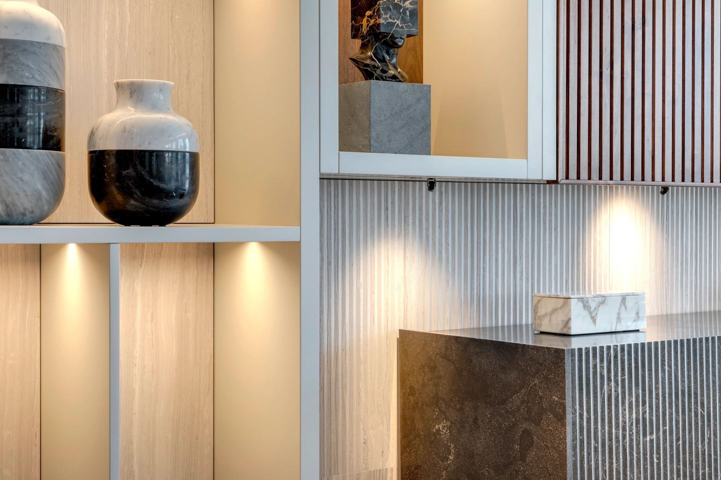 Fluted stone and ceramic vessels in a lit niche