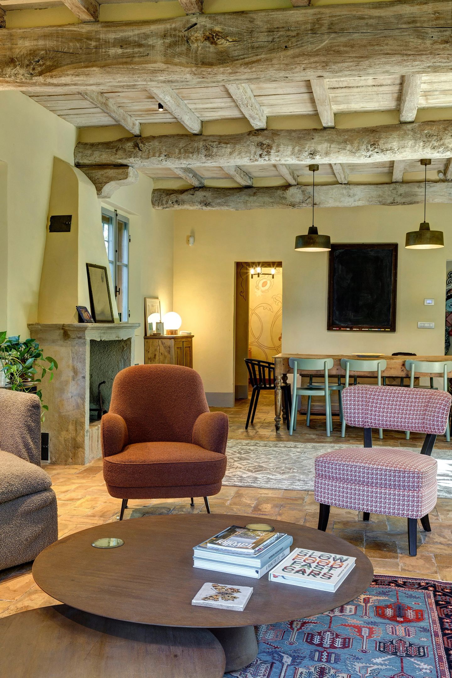 I due tavolini tondi e la poltrona color ruggine, la sala da pranzo alle spalle