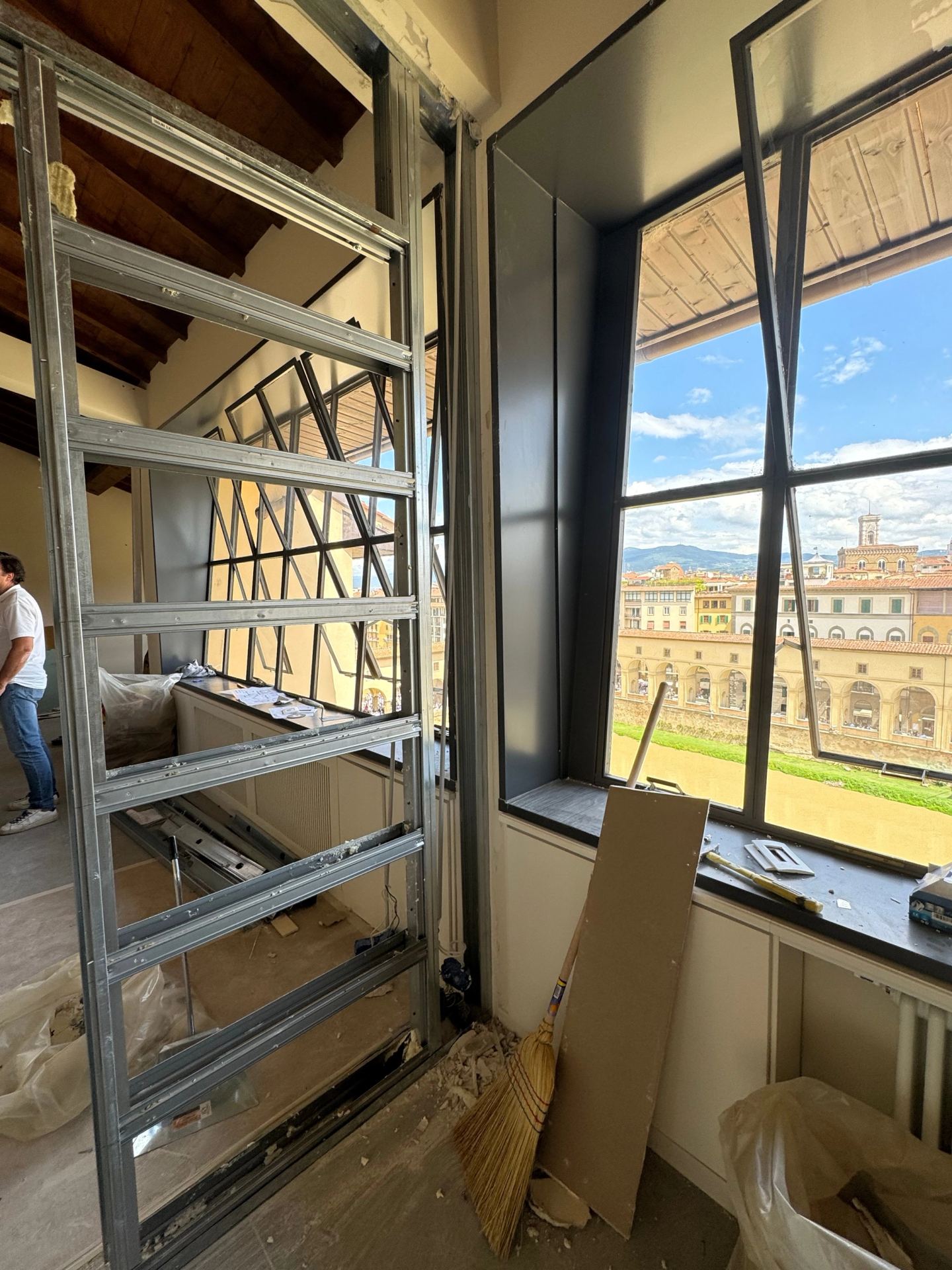 Steel framing rising beside the window wall, the river front beyond