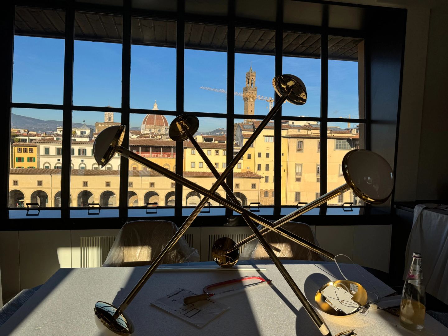 A brass chandelier waiting on a table by the window