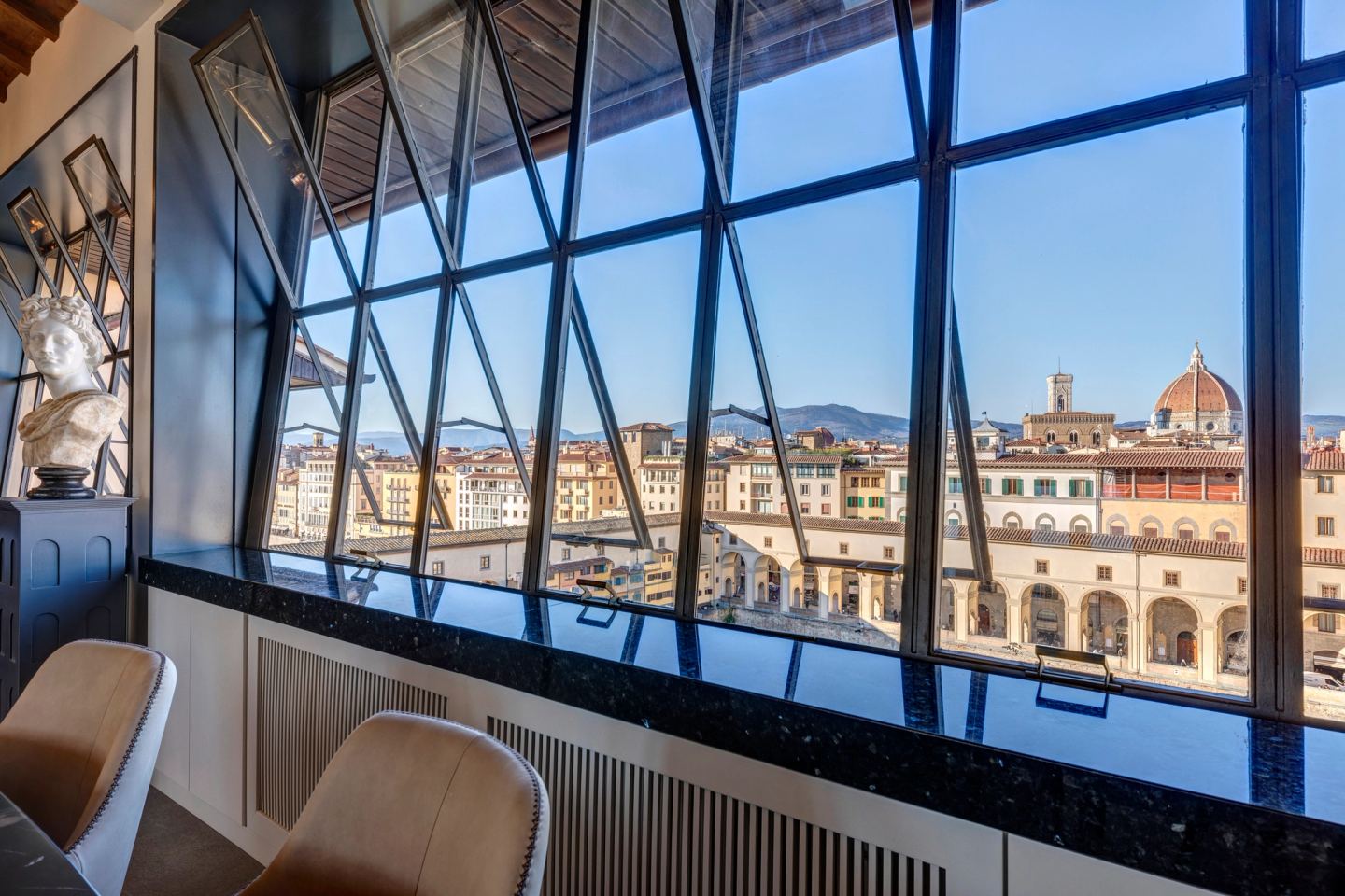 The window wall from inside: Duomo, campanile, the Uffizi below