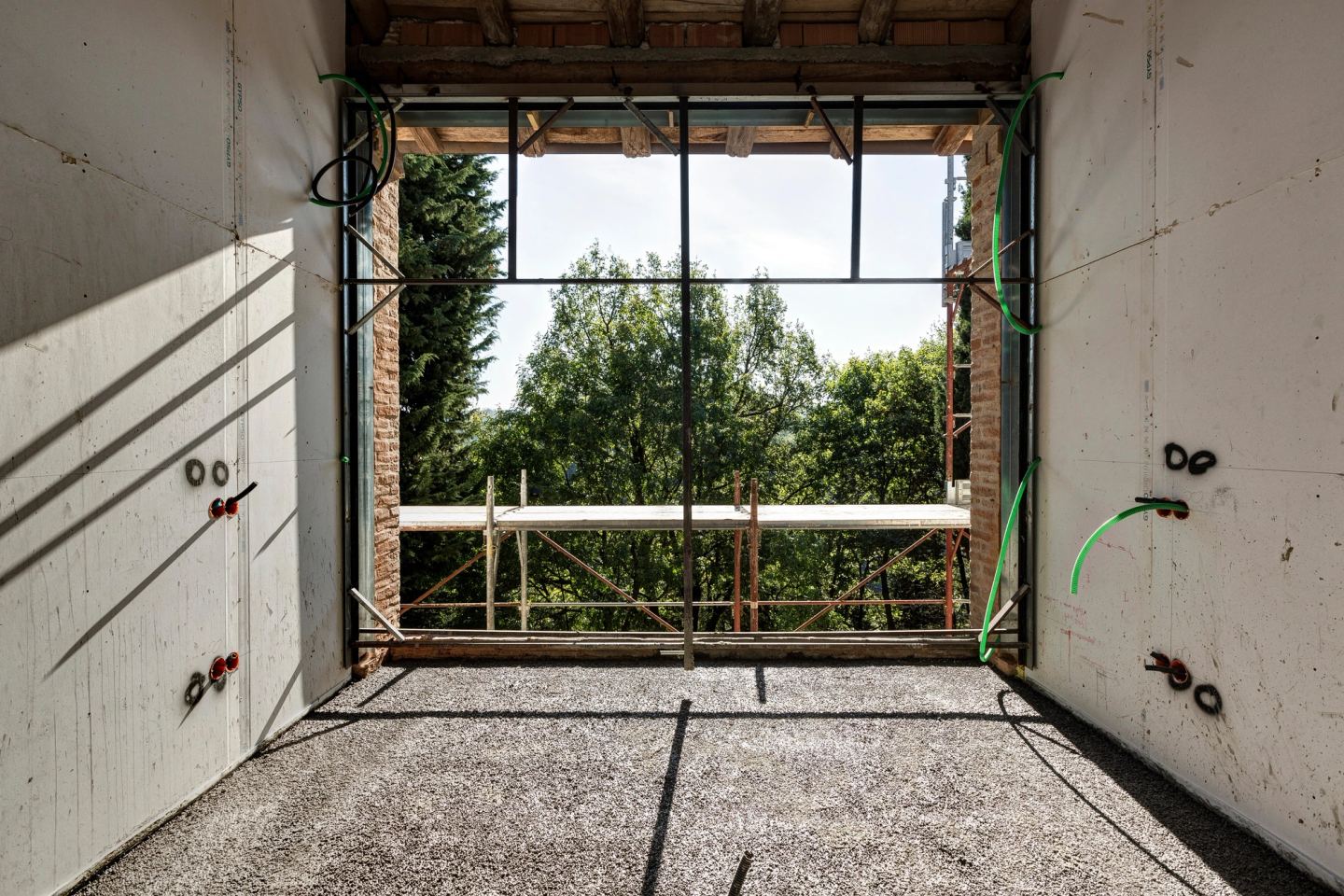 The frame of a large window before the glass, the trees beyond