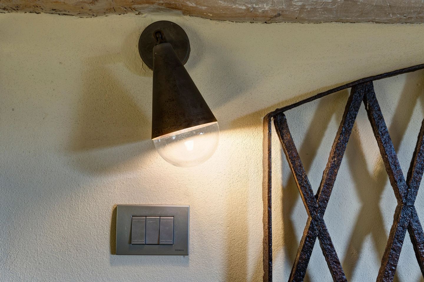 A wall lamp above the iron headboard