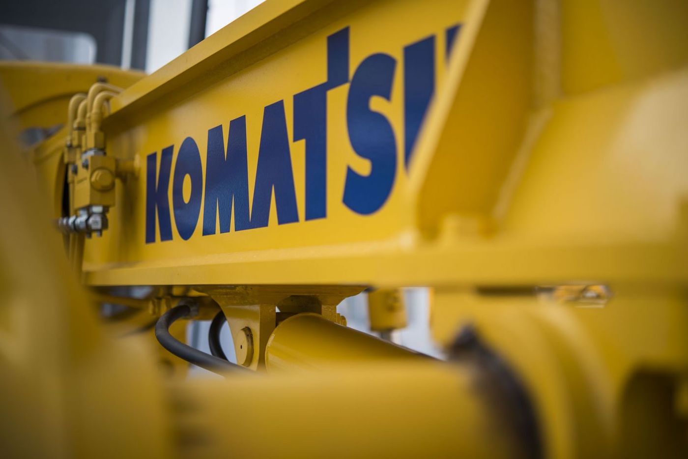 Close-up of blue Komatsu logo on the yellow body of heavy construction machinery
