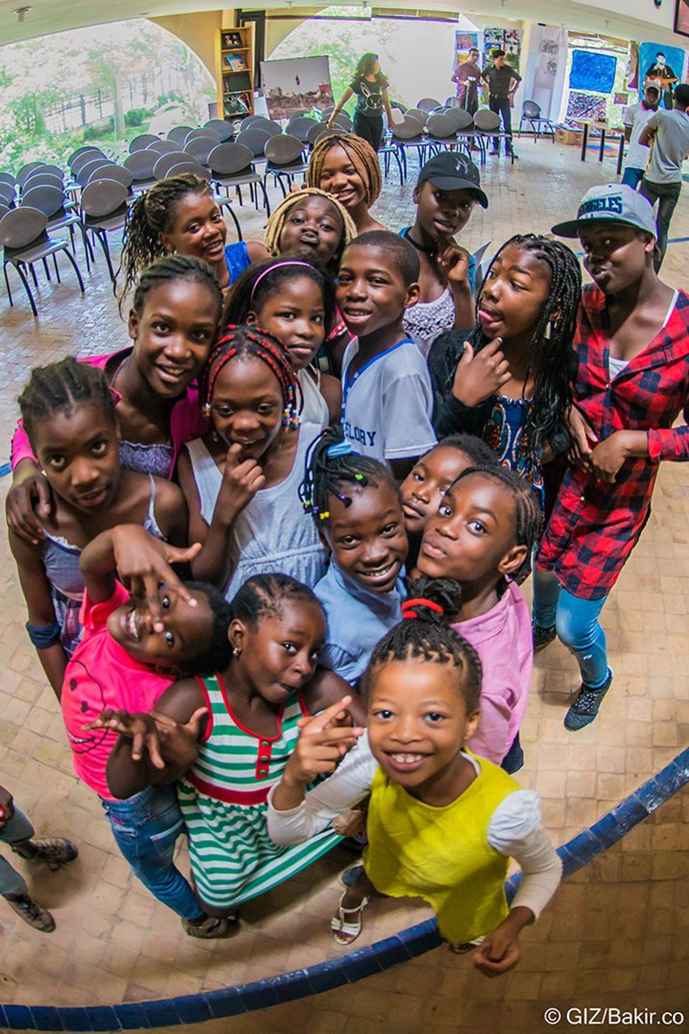 Group of smiling children gathered together, viewed from above with a wide-angle lens, indoors