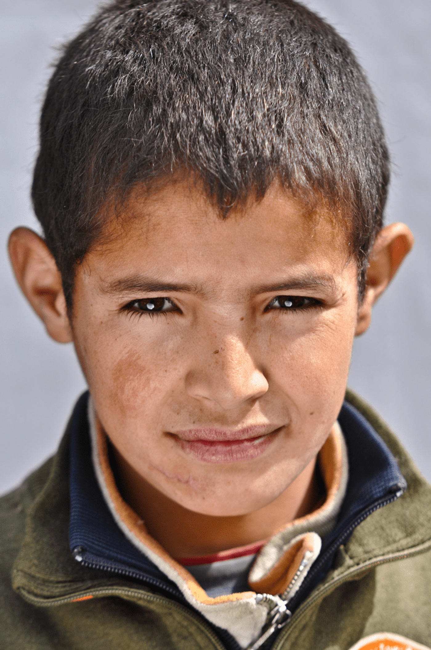 Close-up portrait of a young Moroccan boy with short dark hair and a faint expression