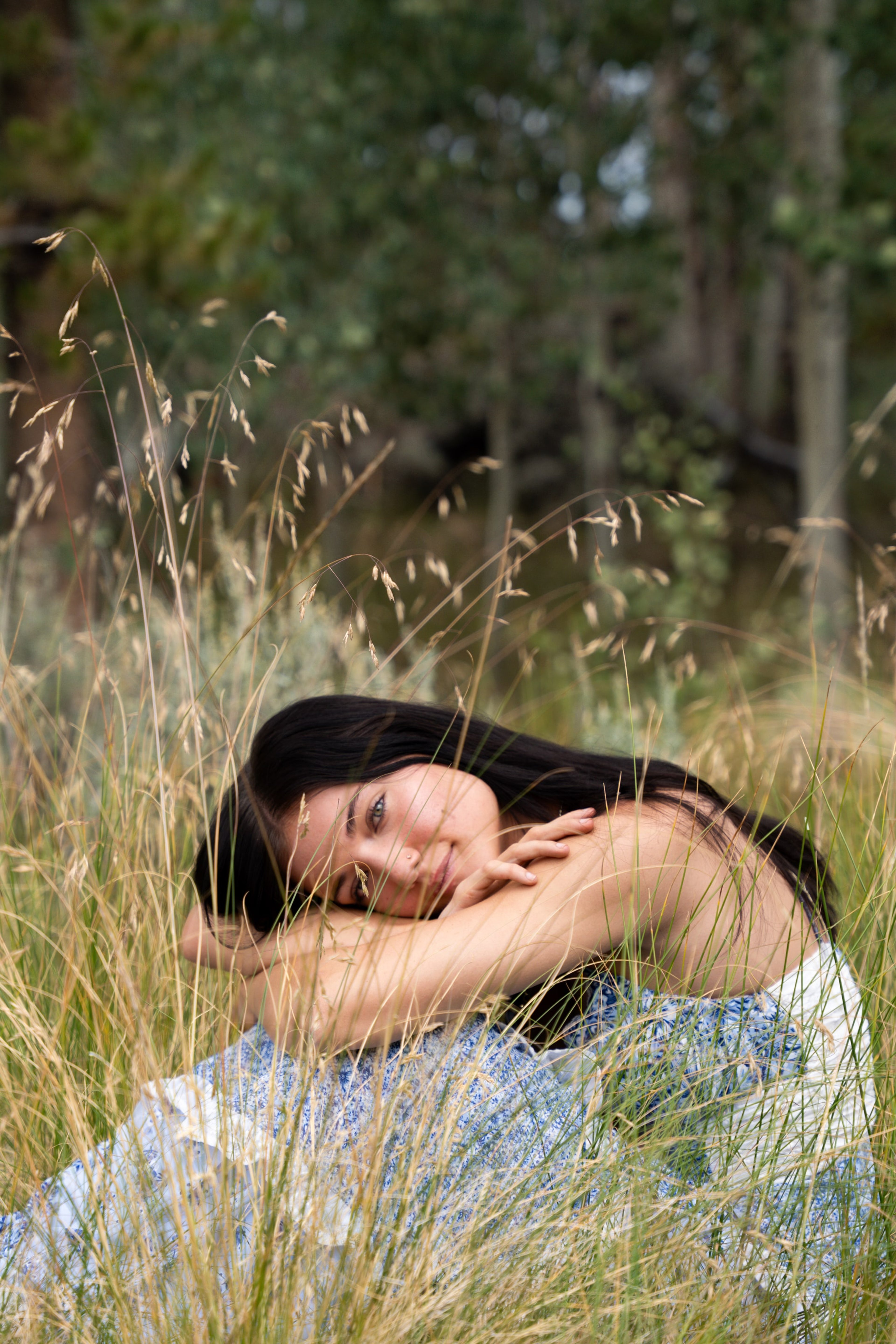 Lucy resting her head on her arms on a creek boulder, smiling