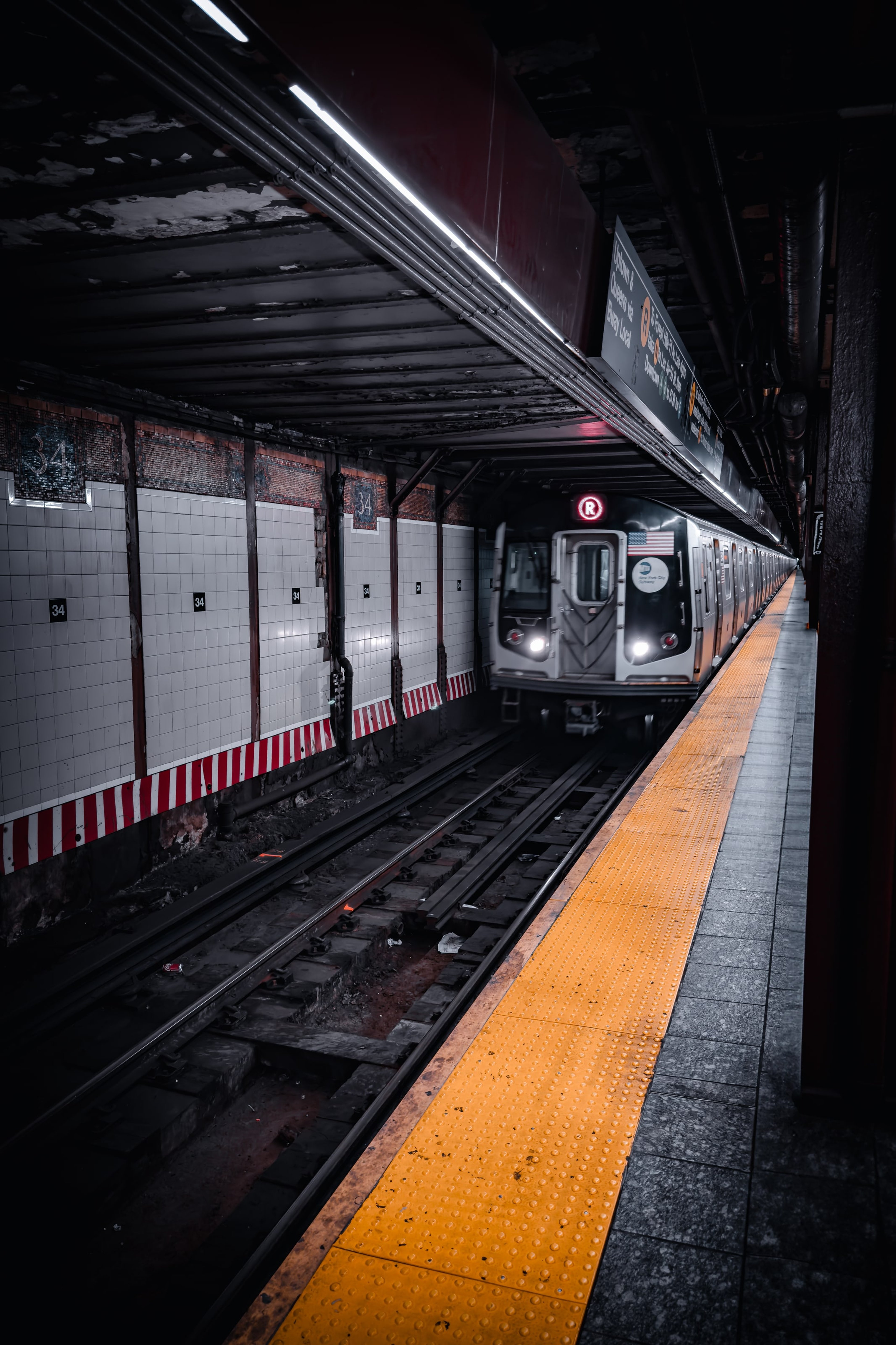A subway train streaking along the platform edge, yellow warning line in the dark