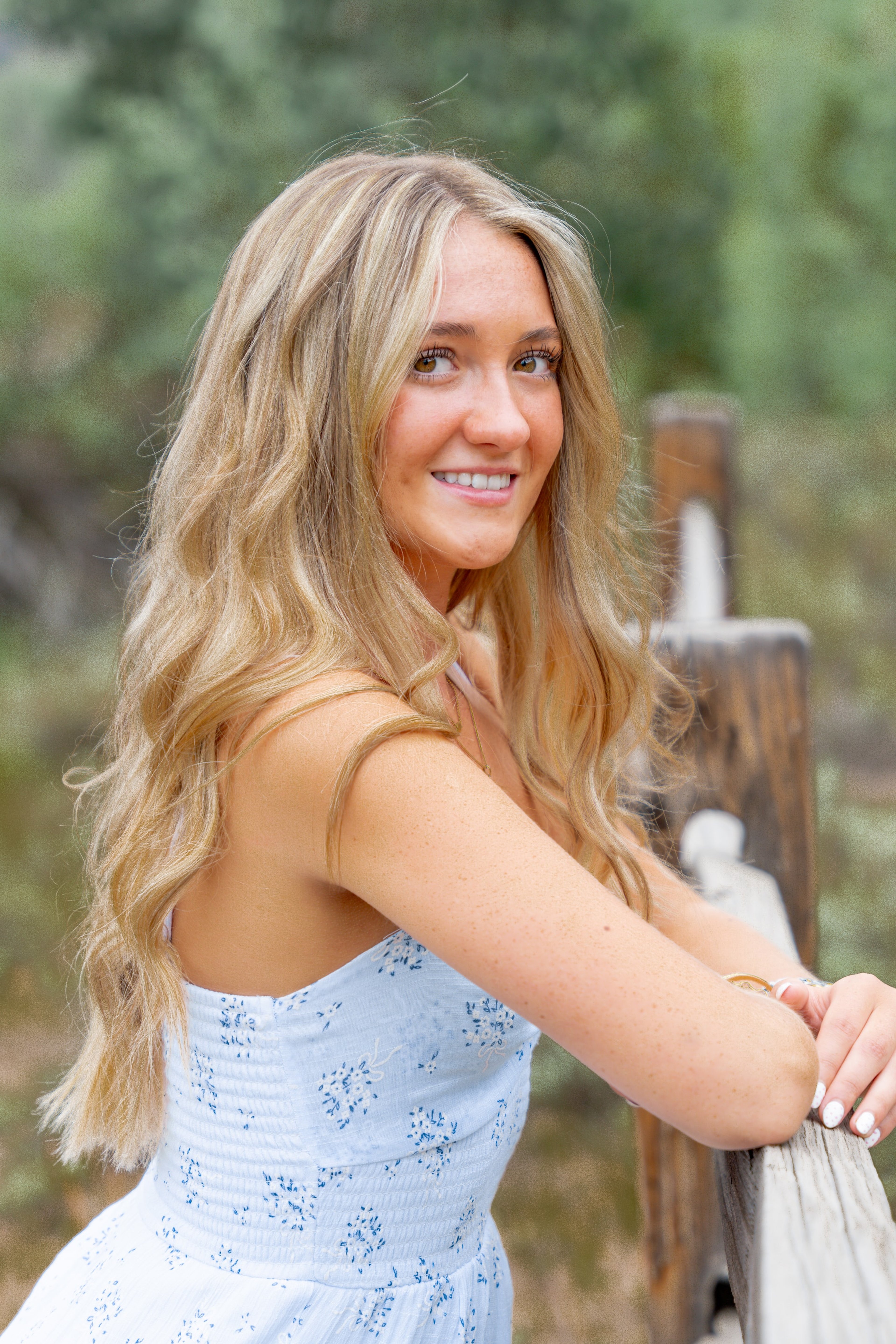 Close portrait of Caleigh smiling over her shoulder beside a fence