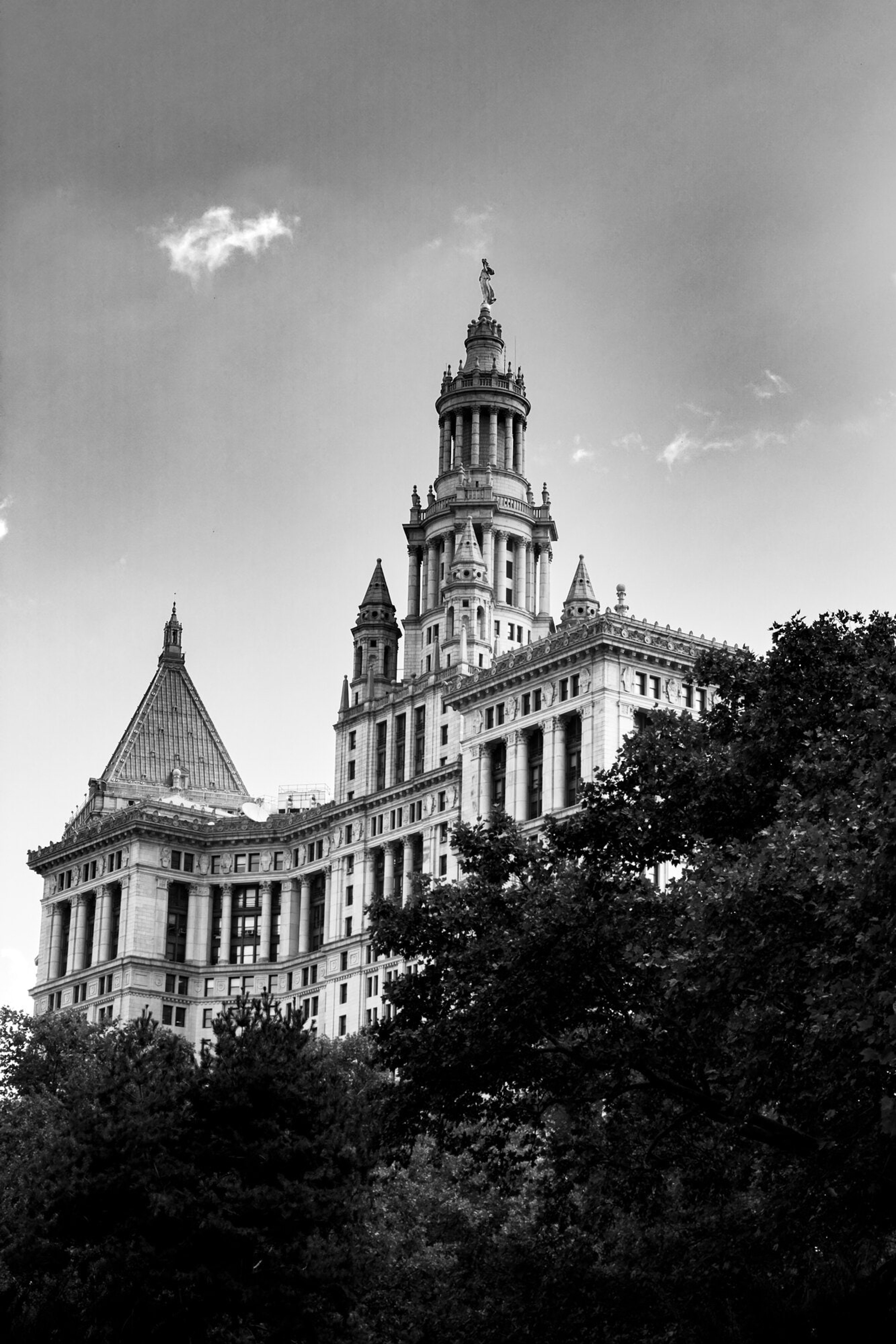 An ornate cathedral tower rising into a broken sky, in black and white