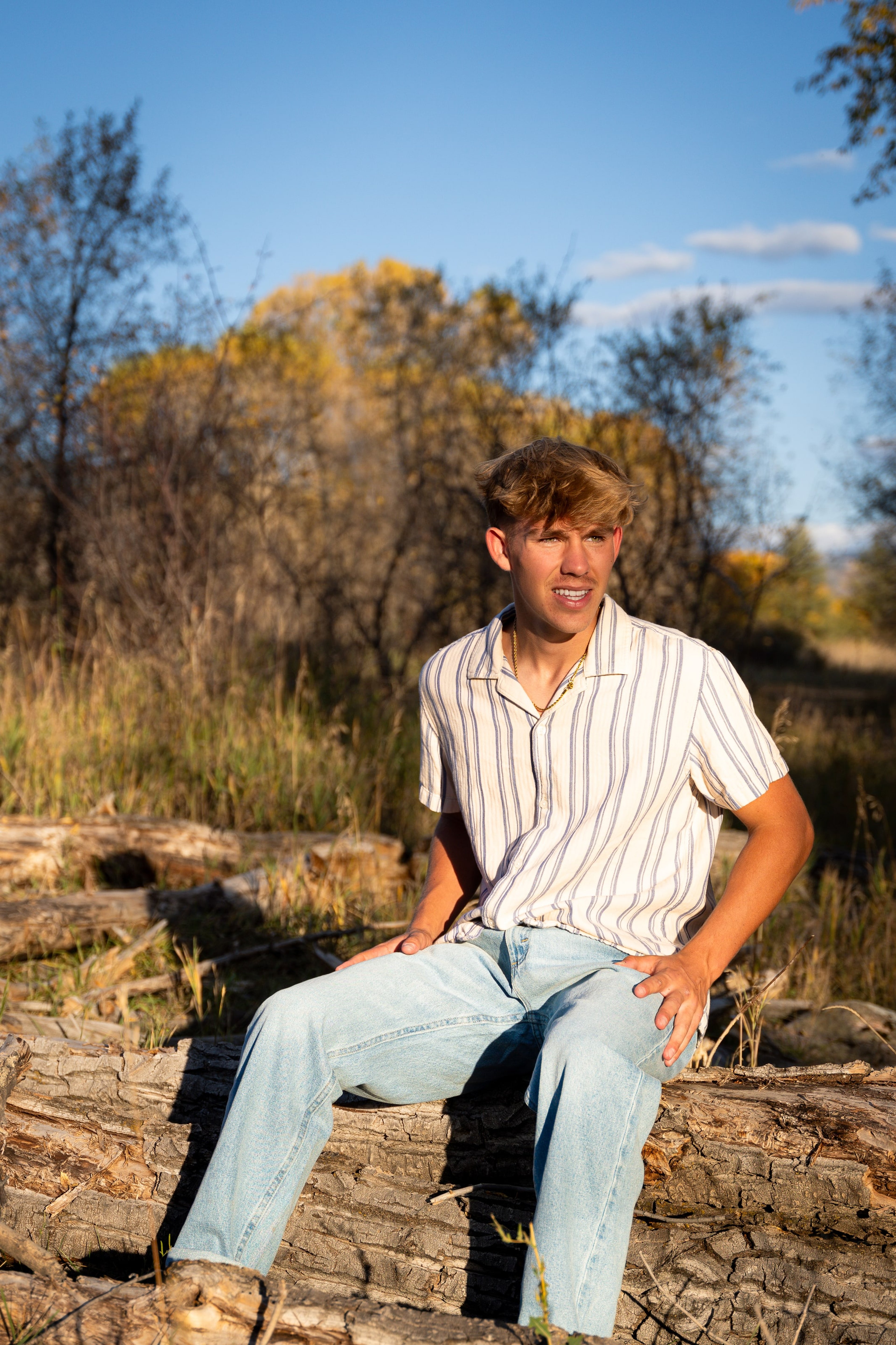 Wyat laughing on the log pile in afternoon sun