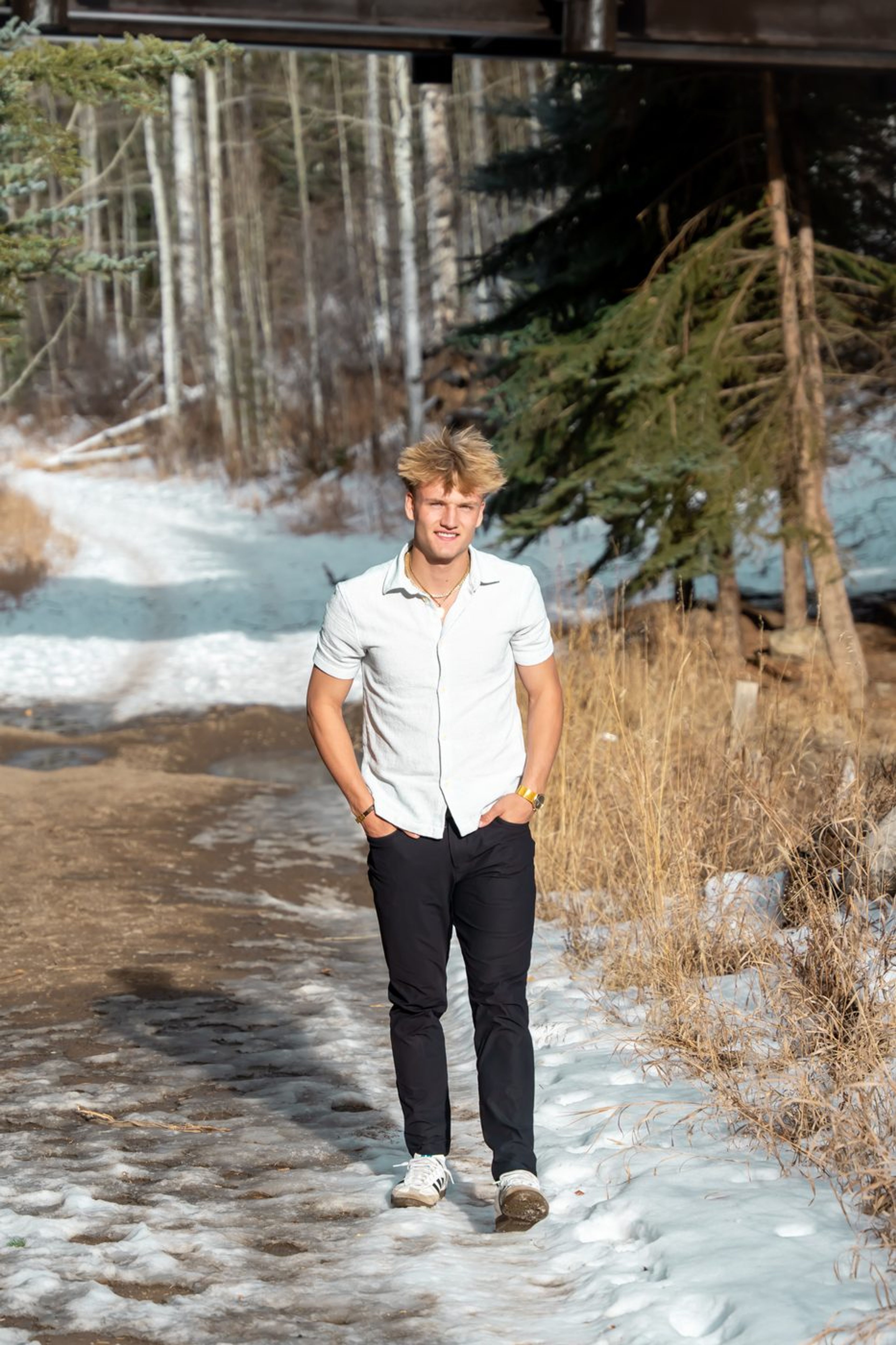 Senior portrait on a snowy forest path in a white shirt