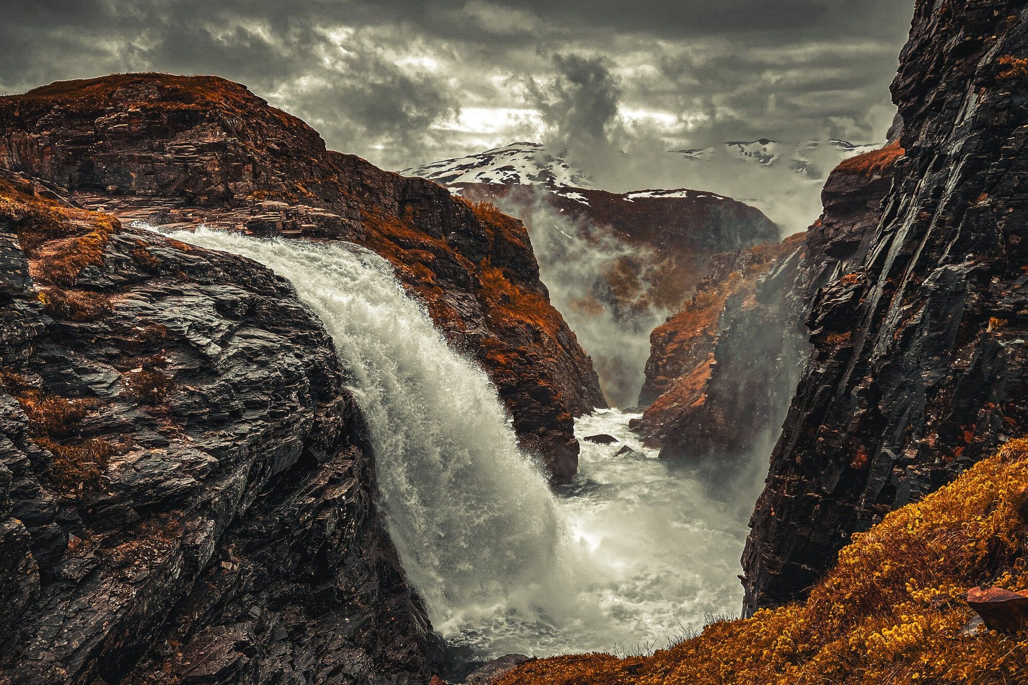 A waterfall pouring through a mossy gorge in autumn rain, Norway